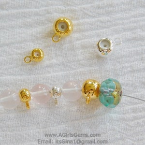 May include: A close-up of a bracelet with gold and silver beads, including a pink quartz bead, a clear crystal bead, and a turquoise bead. The bracelet is strung on a thin wire.