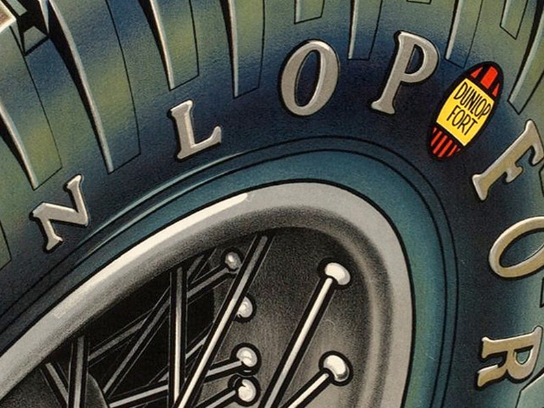 May include: Close-up of a blue tire with the word "DUNLOP FORT" in white lettering on a yellow oval sticker. The tire also has the word "DUNLOP" in silver lettering on the side.
