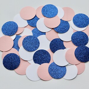 Peut inclure: Une collection de cercles en papier pailleté bleu, rose et blanc. Les cercles sont disposés de manière aléatoire et sont tous de la même taille.