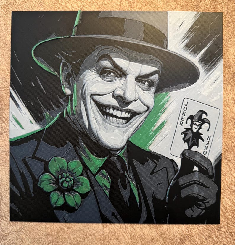 Peut inclure: Impression carr&eacute;e repr&eacute;sentant un portrait stylis&eacute; du Joker. Le Joker sourit largement, portant un costume sombre, une chemise verte et un chapeau. Il tient une carte de jeu Joker. L'&oelig;uvre utilise une palette de couleurs limit&eacute;e : noir, vert et blanc.