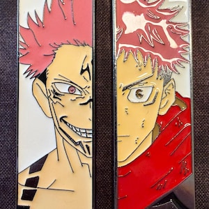 May include: Two rectangular enamel pins featuring anime character art. One pin shows a character with red spiky hair and a sinister grin, the other shows a character with red hair and a determined expression. Both pins have a silver border.
