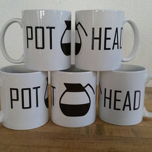 Könnte beinhalten: Vier weiße Keramikbecher mit schwarzem Text und einer Kaffeekanne-Grafik. Die Becher tragen den Schriftzug "POT HEAD" auf der Vorderseite.
