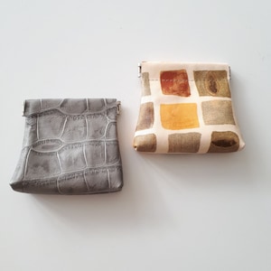 Monedero pequeño de piel elaborado en piel estampada única. Una bolsa de cuero con marco apretable.