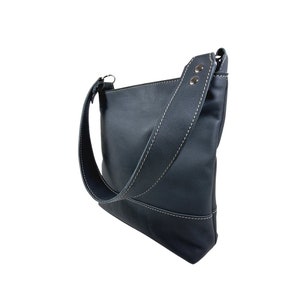 Bolso bandolera de piel negra hecho a mano. Diseño minimalista y tamaño suficiente para uso diario.
