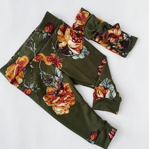 May include: A pair of green leggings with a floral print featuring yellow, orange, and red roses. A matching green headband with a bow is included.