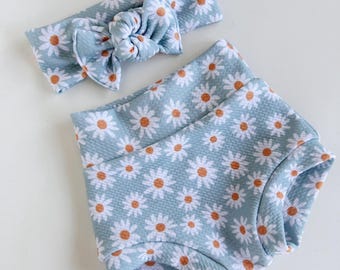 Può includere: Un set di fascia per capelli e bloomers per neonati di colore azzurro con stampa di margherite bianche. La fascia è legata a fiocco.