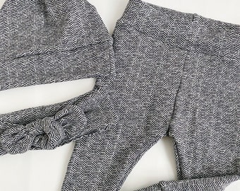 May include: A matching baby set in a black and white herringbone pattern. The set includes a knotted cap, a headband, and a pair of leggings. The leggings have a fitted design with ribbed cuffs. The fabric has a soft, textured appearance.