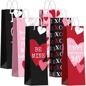 May include: Set of six Valentine's Day gift bags with different designs. The bags are black, pink, and red with hearts, XOXO, and the text "Be Mine" and "Happy Valentine's Day".