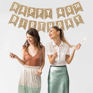 Two friends celebrating a 40th birthday with gold glitter banners that read "Happy 40th Birthday" and sparklers.