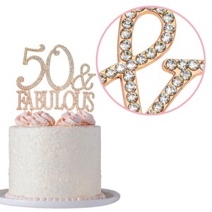 May include: Gold cake topper with rhinestones that says "50 & Fabulous".
