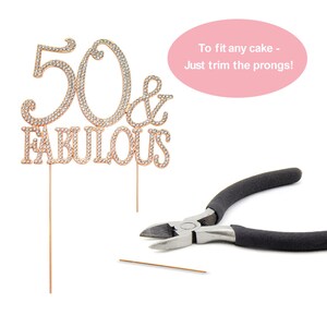 May include: Gold cake topper with rhinestones that says "50 & Fabulous". The topper comes with two prongs that can be trimmed to fit any cake. A pair of wire cutters is shown in the image.