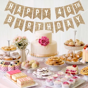 A gold glitter banner with the text "Happy 40th Birthday" hangs above a table with a variety of desserts, including cupcakes, cake pops, and a two-tiered cake.