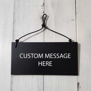 May include: Black wooden sign with a white string hanging from the top. The sign has the text "CUSTOM MESSAGE HERE" printed in white.