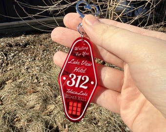 May include: Red plastic keychain shaped like a motel key with the text "Waiting for you Lake View Hotel 312 Toluca Lake Silent Hill" and a row of four red squares.