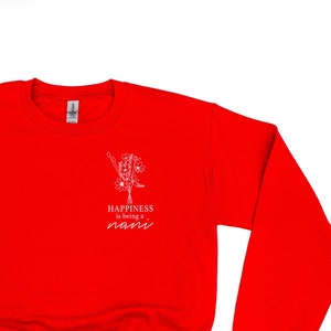 Op de afbeelding: Rood sweatshirt met een witte afbeelding die "Happiness is being a mom" zegt met een bloemmotief.