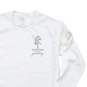 Könnte beinhalten: Weißer Pullover mit einem schwarzen Aufdruck eines Blumenstraußes und dem Text "Happiness is being a granny".