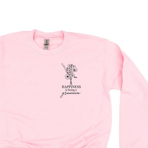 Könnte beinhalten: Ein rosa Sweatshirt mit einem schwarzen Blumenmuster und dem Text "Happiness is being a grandma".