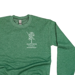 Könnte beinhalten: Grüner Sweatshirt mit einem weißen Grafikdesign, auf dem "Happiness is being a mess" steht.