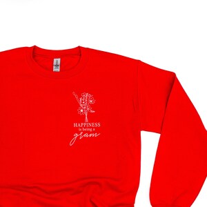 Könnte beinhalten: Roter Pullover mit einem weißen Aufdruck, der "Happiness is being a gram" mit einem stilisierten Blumendesign sagt.