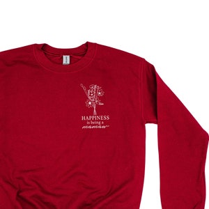 Könnte beinhalten: Roter Pullover mit einem weißen Aufdruck eines Blumenstraußes und dem Text "Happiness is being a mamaa".