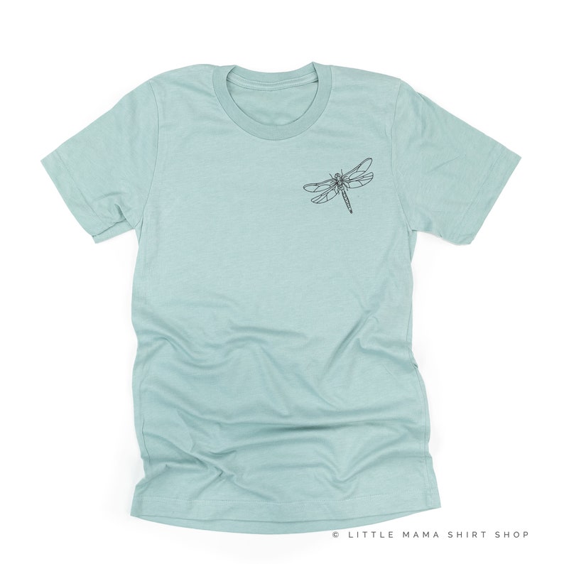 Op de afbeelding: Lichtblauw t-shirt met een zwarte libelafbeelding op de linkerborst. Het shirt heeft korte mouwen en een ronde hals. De tekst "LITTLE MAMA SHIRT SHOP" staat rechtsonder.