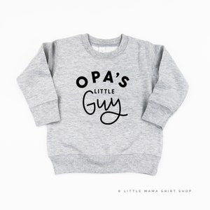 Peut inclure: Sweat-shirt gris avec un texte noir qui dit "OPA'S LITTLE GUY" dans une police de caractères ludique.