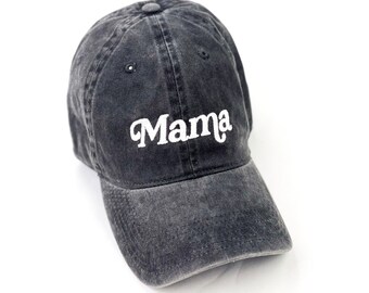 May include: A dark gray baseball cap with the word "Mama" embroidered in white script across the front. The cap has a curved brim and a button on top. The fabric appears to be slightly faded, giving it a vintage look.