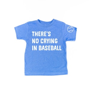 May include: A blue toddler t-shirt with white text that reads "THERE'S NO CRYING IN BASEBALL". A white baseball graphic is on the right sleeve.