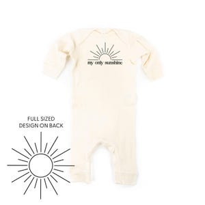 May include: A cream-colored long-sleeved baby onesie with a black sun graphic and the text "my only sunshine". The back of the onesie features a full-sized sun graphic.