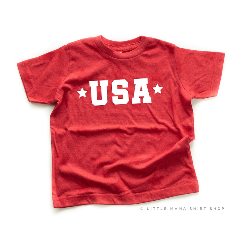 May include: Red t-shirt with white stars and the word "USA" printed on the front.