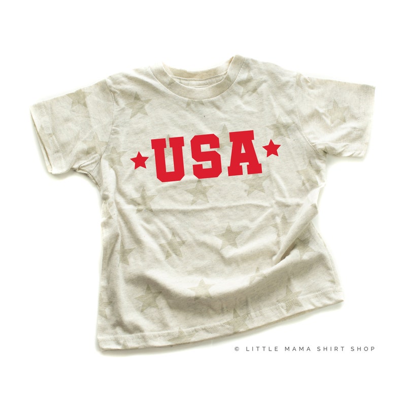May include: A white t-shirt with a star pattern and the word "USA" in red letters.