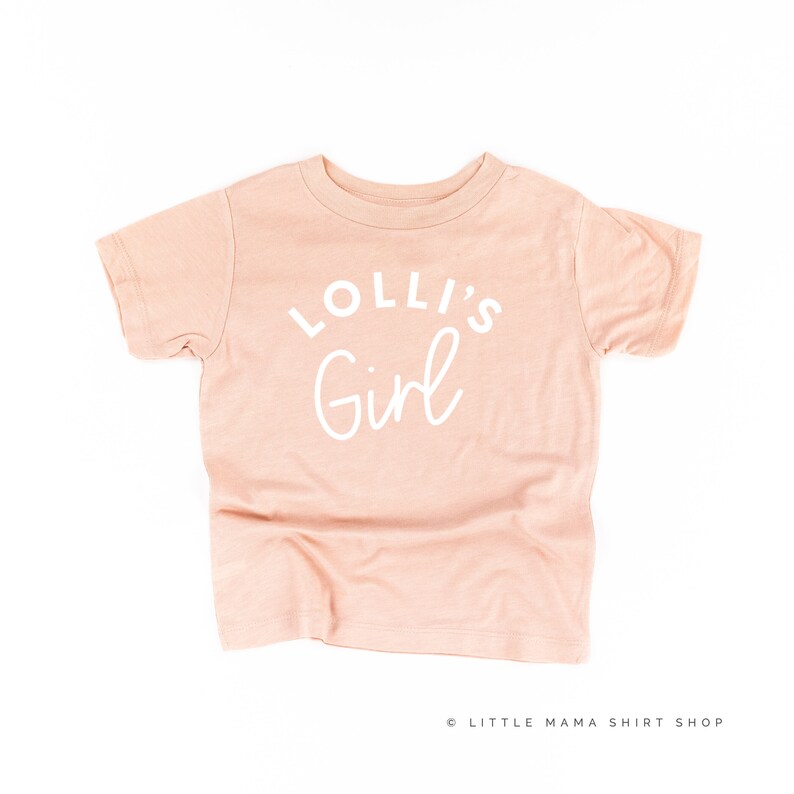 May include: A pale pink t-shirt with the text "Lolli's Girl" in white.