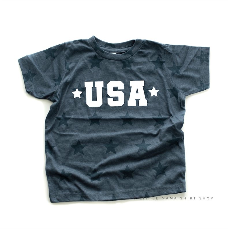 May include: A dark blue t-shirt with a white star pattern and the word "USA" in white letters.