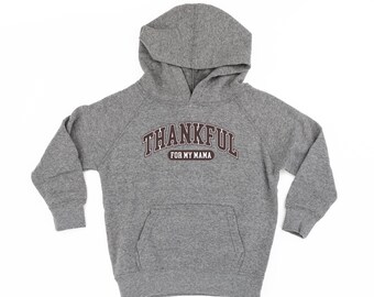 Op de afbeelding: Een grijze hoodie met een voorzak en de tekst "THANKFUL FOR MY MAMA" in een bordeauxrood en wit boogontwerp. De hoodie heeft een capuchon en lange mouwen.