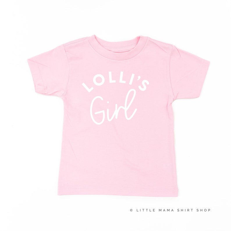 May include: Pink short-sleeved t-shirt with white text that reads "Lolli's Girl".