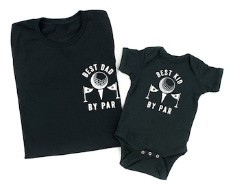 May include: Black t-shirt with white text that says "Best Dad By Par" and a golf ball graphic. A black baby onesie with white text that says "Best Kid By Par" and a golf ball graphic.