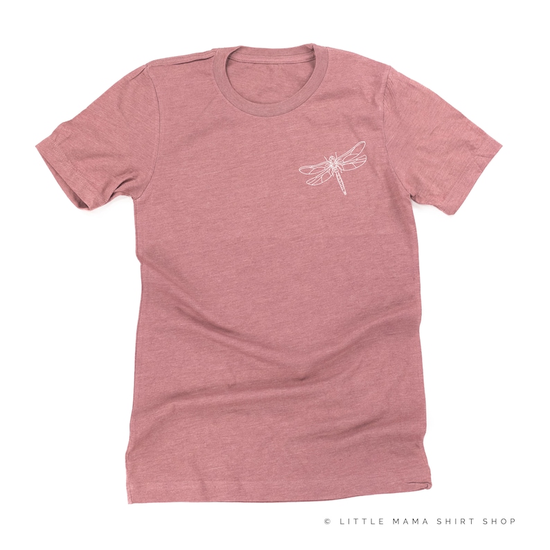 Op de afbeelding: Een stoffig roze t-shirt met een witte libel-omtrek op de linkerbovenborst. Het shirt heeft korte mouwen en een ronde hals. De tekst "LITTLE MAMA SHIRT SHOP" staat rechtsonder.
