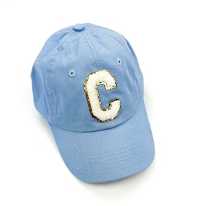 May include: A light blue baseball cap with a white felt letter "C" with gold glitter accents.