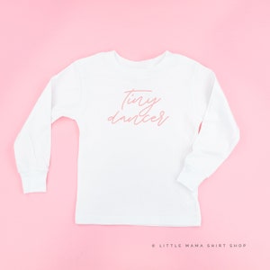 May include: White long-sleeved shirt with the words "tiny dancer" written in pink on the front.