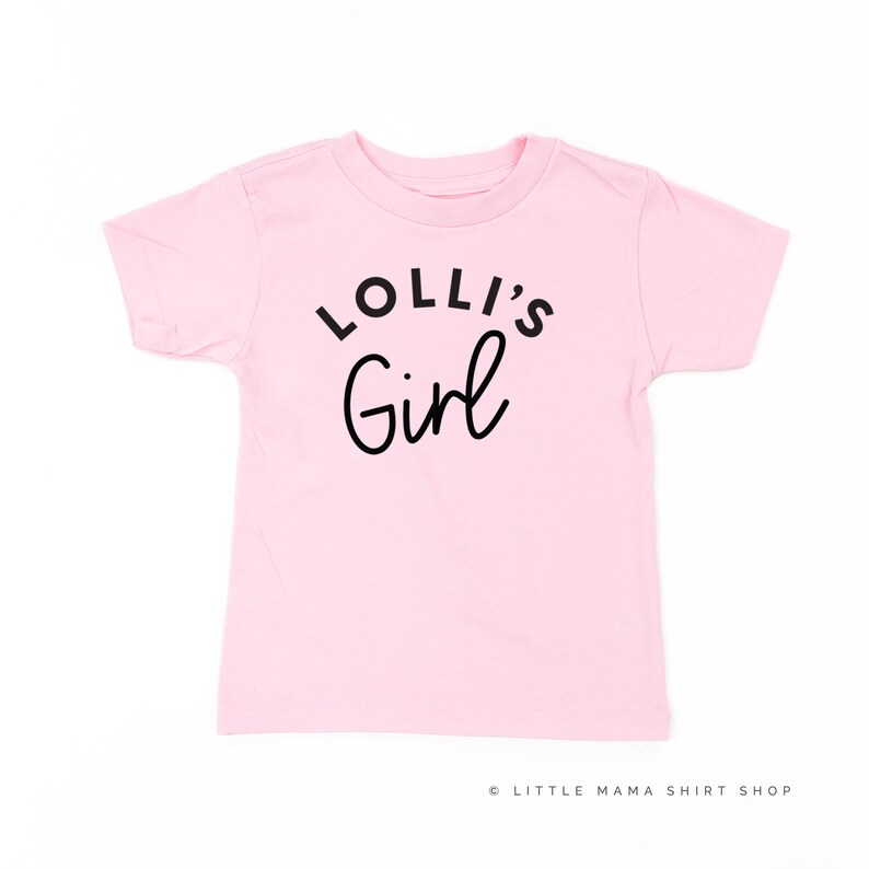 May include: Pink short-sleeved t-shirt with black text that reads "Lolli's Girl".