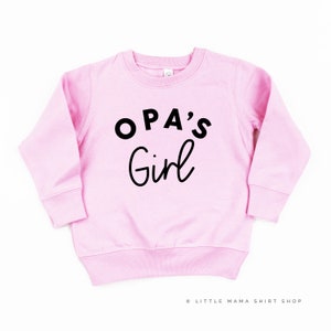 Peut inclure: Sweat-shirt rose à manches longues avec un texte noir qui dit "OPA'S Girl".