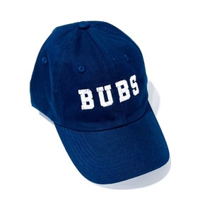 May include: A navy blue baseball cap with a white embroidered logo that says "BUBS".