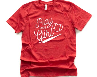 Op de afbeelding: Rood T-shirt met witte tekst die "Play Like A Girl" zegt met een baseball en knuppel afbeelding.