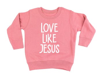 Peut inclure: Un sweat-shirt rose clair avec l'inscription blanche "LOVE LIKE JESUS". Ce haut à manches longues et col rond est fabriqué dans une matière douce et convient aux enfants.