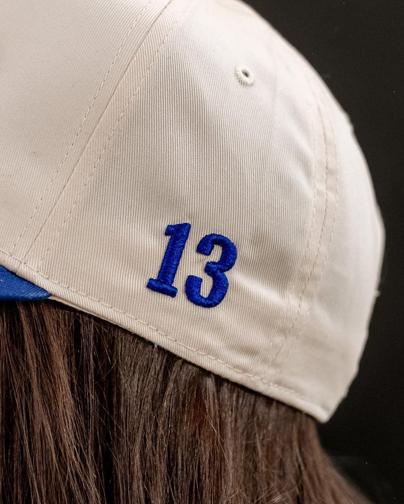 May include: A white baseball cap with a blue number 13 embroidered on the back.