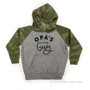 Peut inclure: Un sweat à capuche gris et vert camouflage avec un imprimé noir qui dit "OPA'S LITTLE GUY".