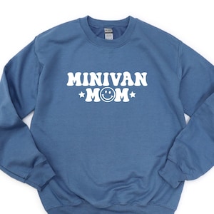 May include: A blue crewneck sweatshirt with the text "MINIVAN MOM" in white, featuring a smiley face and stars. The sweatshirt has long sleeves and a ribbed neckline, cuffs, and hem.