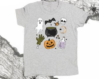 Könnte beinhalten: Ein hellgraues T-Shirt mit Halloween-Illustrationen. Das Design umfasst einen Geist, eine Fledermaus, eine Spinne, einen Totenkopf, einen Kessel, einen Mond, Zuckermais, eine Zaubertrankflasche und einen Kürbis. Das Shirt besteht aus einem weichen Material.
