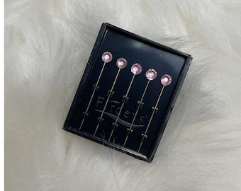 May include: A black box containing six silver pins with pink rhinestone heads. The box has the word "Edges" printed on it.