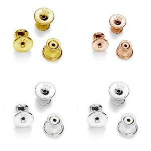 Puede incluir: Seis cierres para pendientes en tres colores diferentes: oro, oro rosa y plata. Cada cierre tiene una parte superior redonda, plana y pequeña con un agujero en el centro y una parte inferior redonda, plana y ligeramente más grande con un borde elevado. Los cierres están marcados con el número "925".